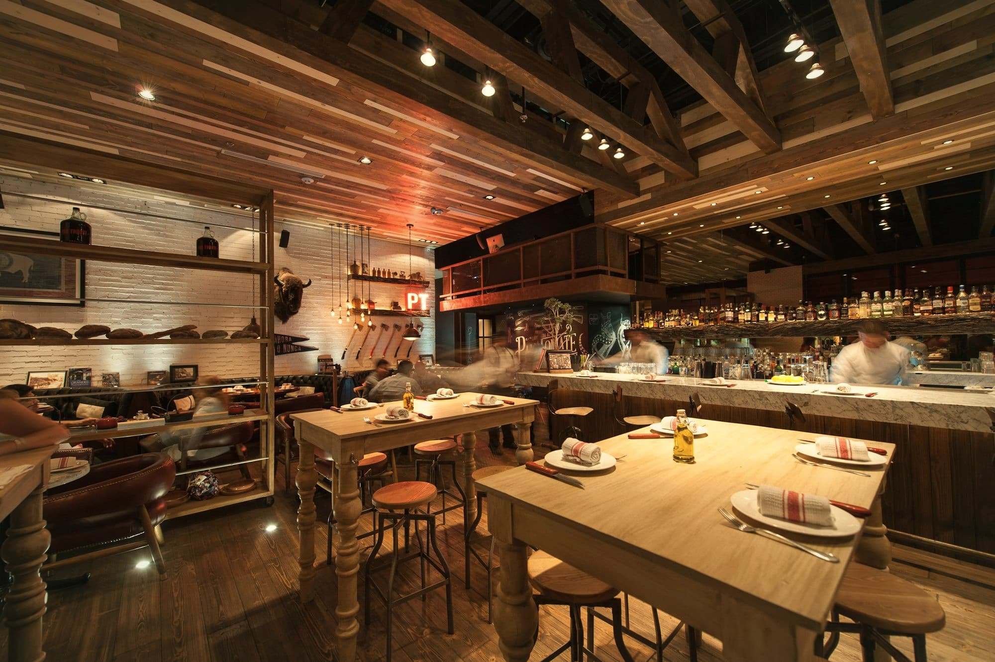 The open kitchen and scrubbed wooden tables at Ortiga, warmly lit in the evening.